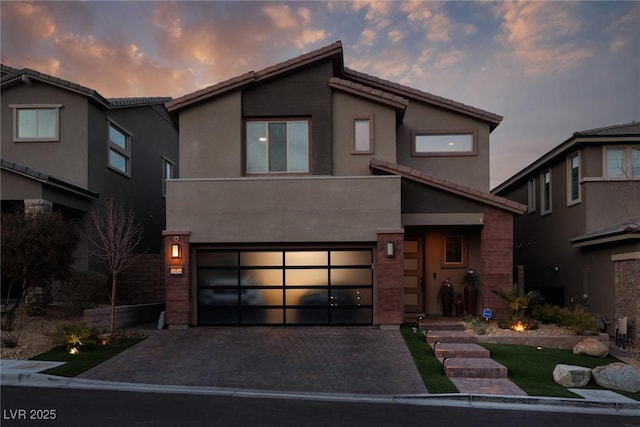 modern home featuring a garage, a tiled roof, decorative driveway, and stucco siding