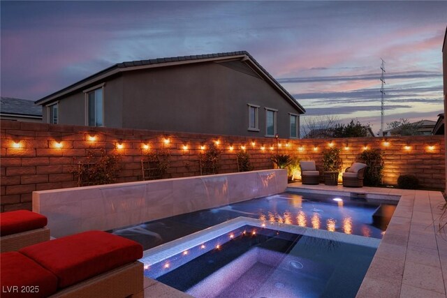 pool at dusk with an in ground hot tub