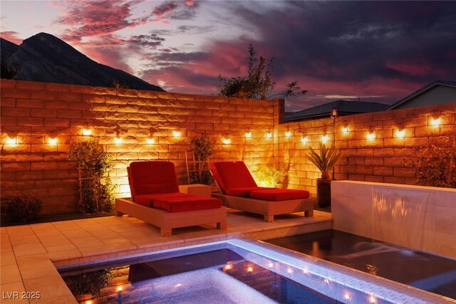 patio terrace at dusk featuring a hot tub