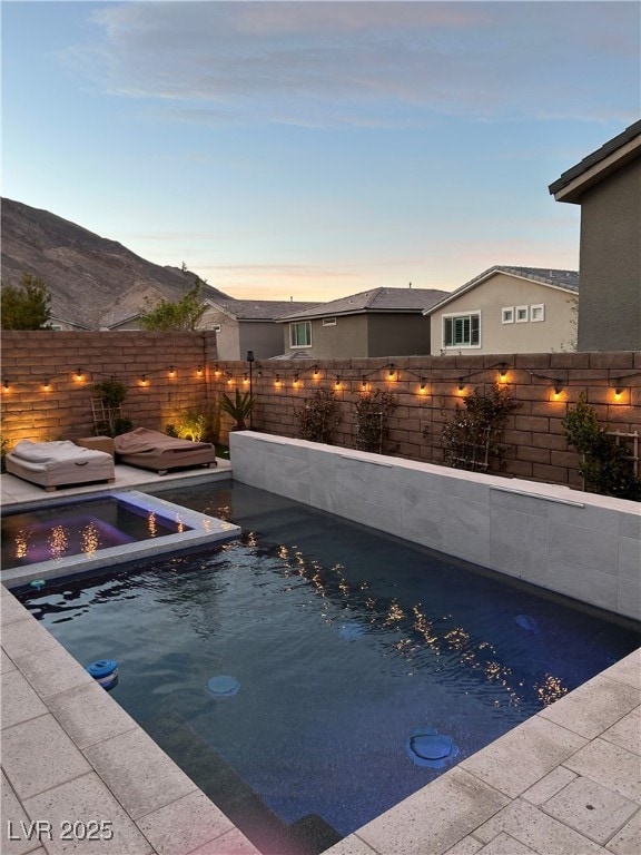 view of swimming pool with a fenced backyard, a mountain view, and a fenced in pool