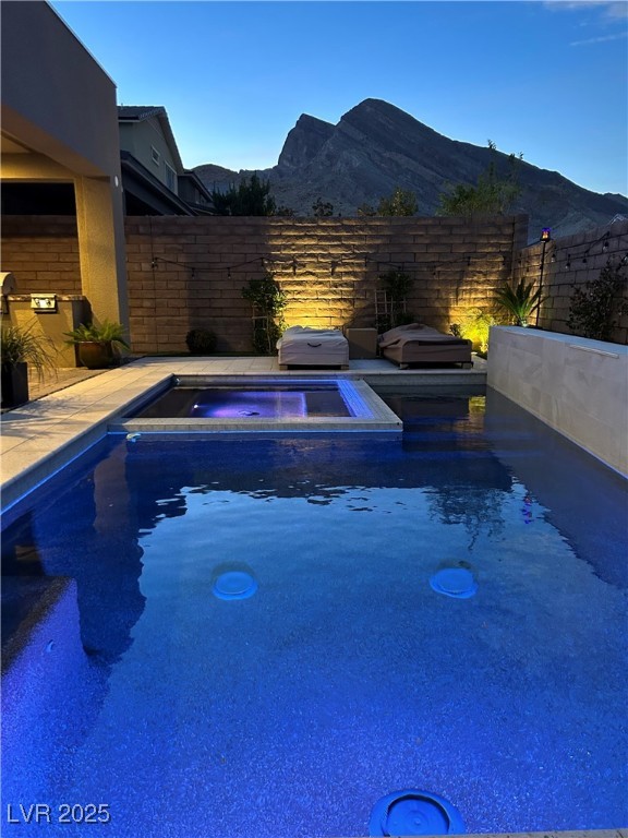 view of pool featuring a mountain view, fence, area for grilling, and an in ground hot tub