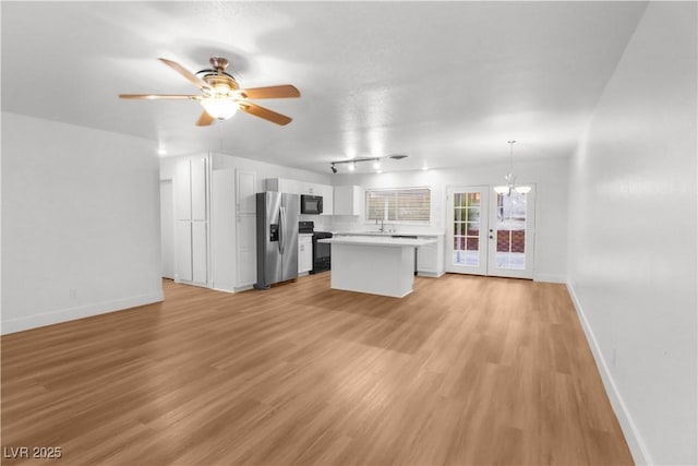 kitchen with a center island, decorative light fixtures, light wood-type flooring, and black appliances