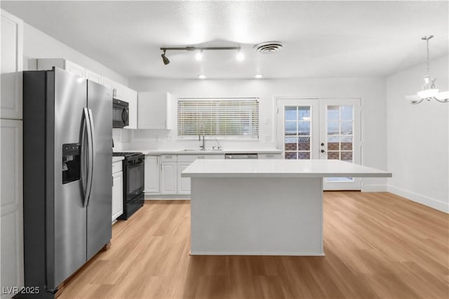 kitchen featuring pendant lighting, sink, black appliances, white cabinets, and a kitchen island