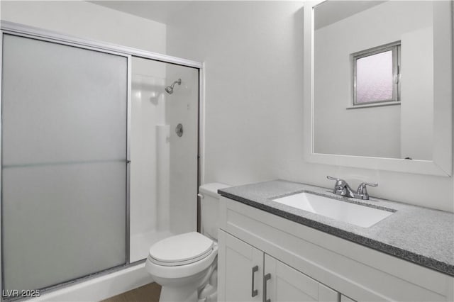 bathroom with an enclosed shower, vanity, and toilet