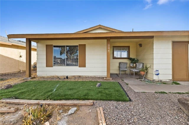 view of exterior entry with a yard and a patio