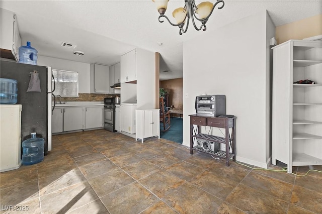 kitchen featuring white cabinetry, sink, a notable chandelier, stainless steel appliances, and a textured ceiling