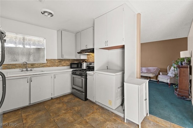 kitchen with sink, stainless steel gas range, refrigerator, white cabinetry, and backsplash