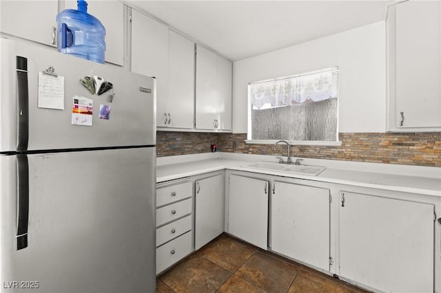 kitchen featuring white cabinetry, sink, tasteful backsplash, and stainless steel refrigerator