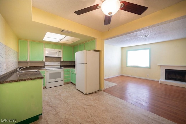 kitchen with sink, white appliances, green cabinetry, ceiling fan, and a fireplace