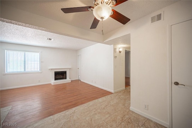 1701 E Katie Ave Unit 65, Las Vegas, NV 89119 - unfurnished living room featuring a textured ceiling, a fireplace, a ceiling fan, light wood-style floors, and baseboards