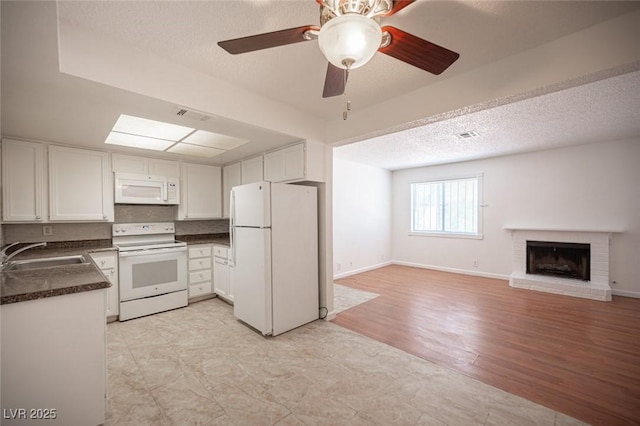 1701 E Katie Ave Unit 65, Las Vegas, NV 89119 - kitchen with white appliances, a sink, dark countertops, white cabinets, and a textured ceiling