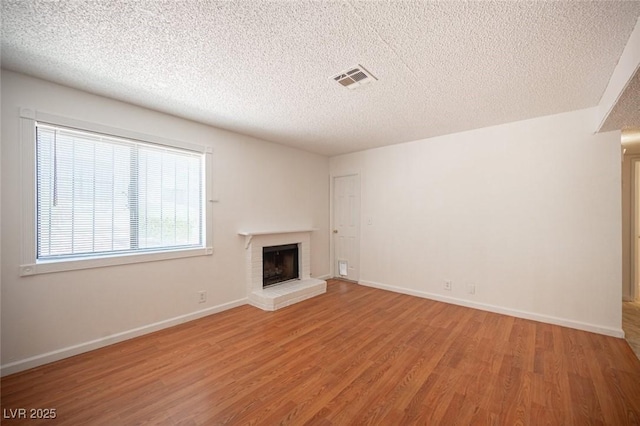 1701 E Katie Ave Unit 65, Las Vegas, NV 89119 - unfurnished living room with wood finished floors, a brick fireplace, a textured ceiling, and baseboards