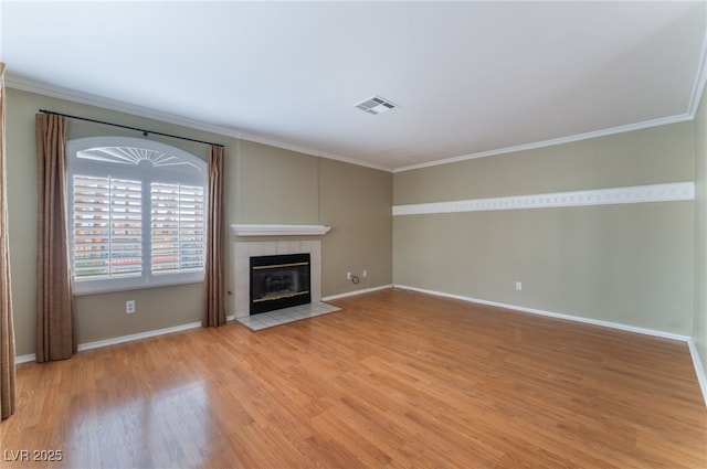 unfurnished living room with a tiled fireplace, ornamental molding, and light hardwood / wood-style flooring