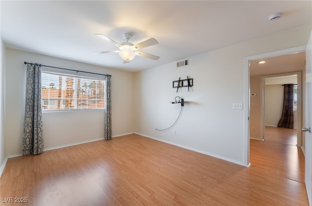 empty room with ceiling fan and light hardwood / wood-style flooring