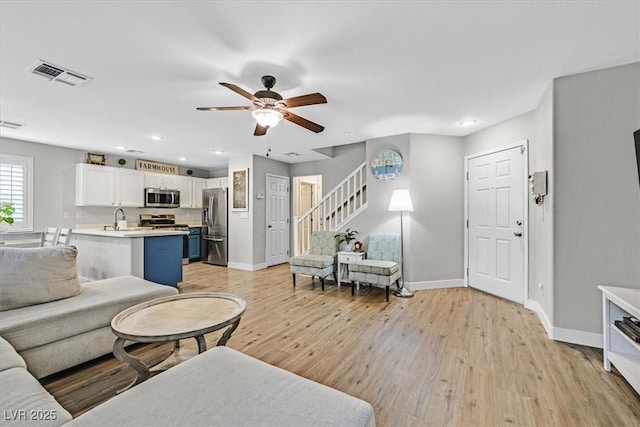 living room featuring ceiling fan, sink, and light wood-type flooring