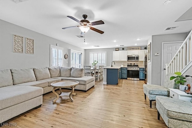 living room with sink, light hardwood / wood-style flooring, and ceiling fan