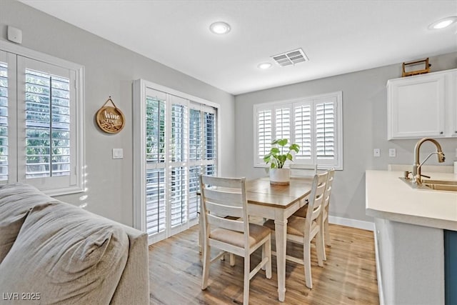 dining area with light wood-type flooring, sink, and a wealth of natural light