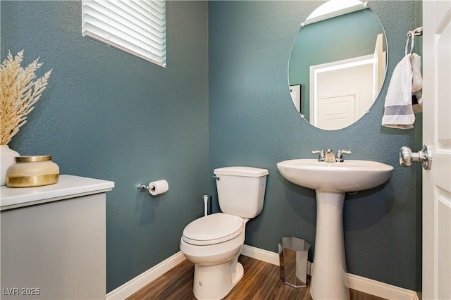 half bathroom with toilet, baseboards, and wood finished floors