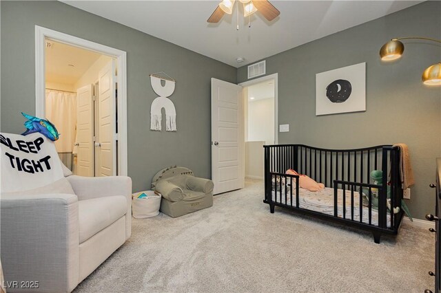 carpeted bedroom featuring ceiling fan and a crib