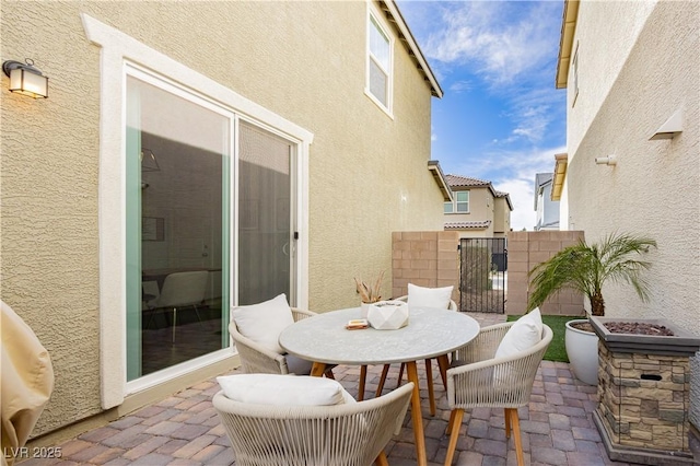 view of patio with an outdoor fire pit, fence, and a gate