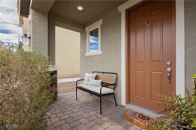 doorway to property featuring covered porch and stucco siding