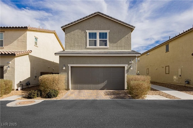 view of front facade with decorative driveway, an attached garage, and stucco siding