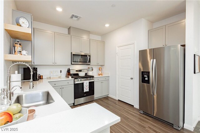 kitchen with hardwood / wood-style flooring, white cabinetry, stainless steel appliances, and sink