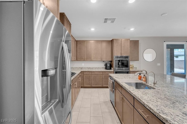 kitchen featuring appliances with stainless steel finishes, sink, light tile patterned floors, and light stone counters