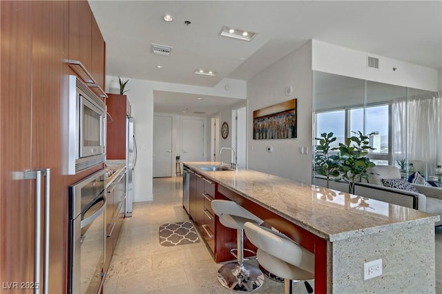 kitchen featuring light stone countertops, sink, a kitchen bar, and a spacious island