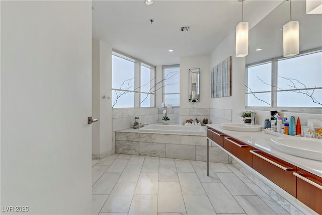 bathroom featuring vanity and a relaxing tiled tub