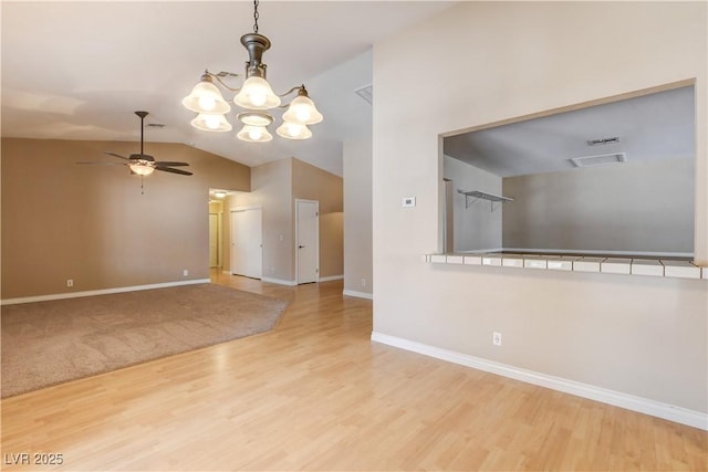 unfurnished room featuring hardwood / wood-style flooring, lofted ceiling, and ceiling fan with notable chandelier