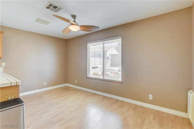 unfurnished living room with radiator, ceiling fan, and light wood-type flooring