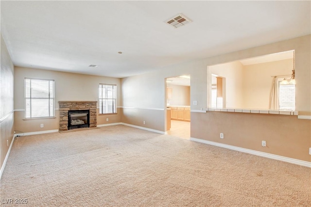 unfurnished living room featuring a stone fireplace and light colored carpet