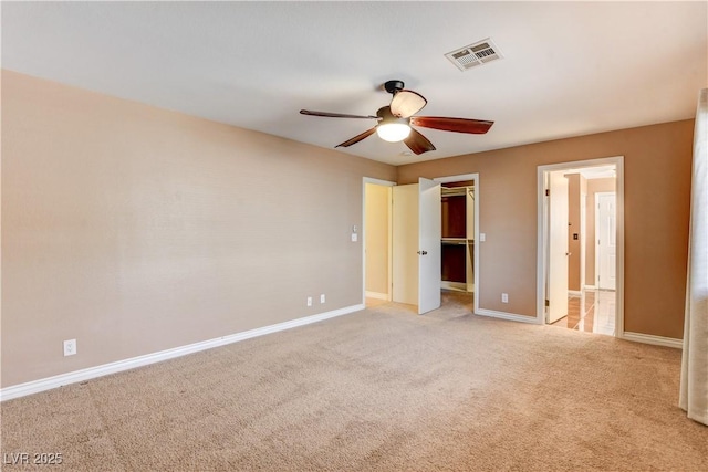 unfurnished bedroom with ceiling fan, a spacious closet, a closet, and light carpet