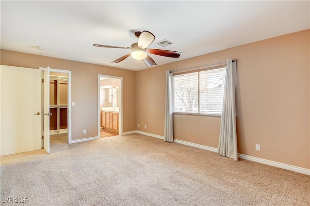 unfurnished bedroom featuring ceiling fan, light colored carpet, and ensuite bath