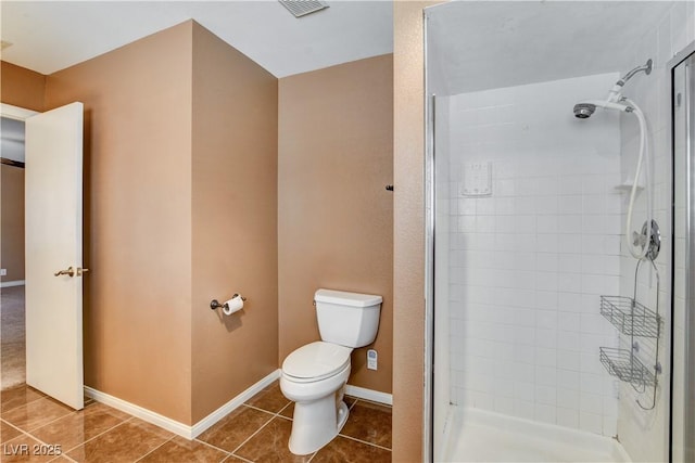 bathroom featuring tile patterned floors, toilet, and a tile shower