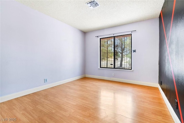 unfurnished room featuring light hardwood / wood-style flooring and a textured ceiling