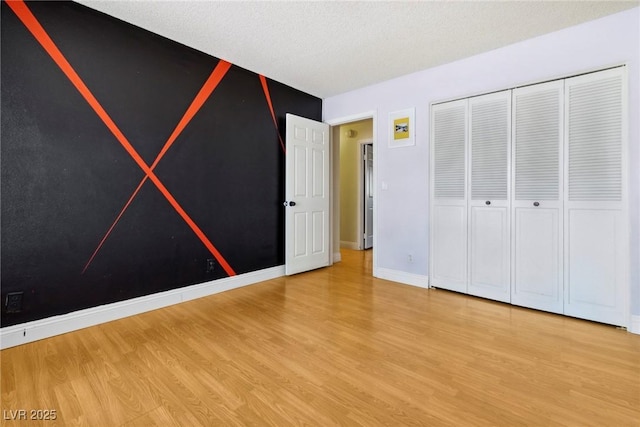 unfurnished bedroom featuring hardwood / wood-style flooring, a closet, and a textured ceiling