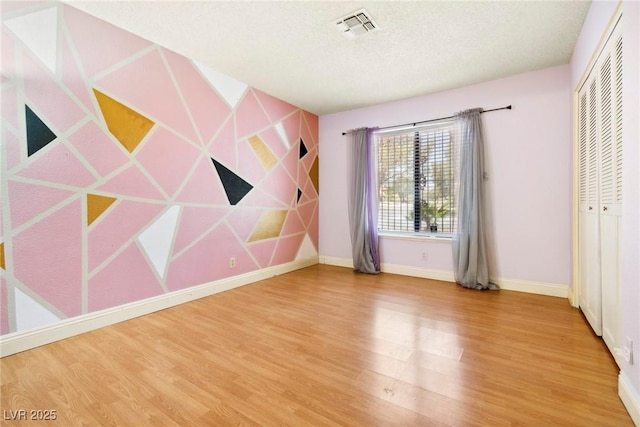 unfurnished bedroom featuring hardwood / wood-style flooring, a closet, and a textured ceiling