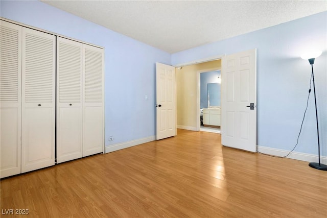 unfurnished bedroom with a closet, a textured ceiling, and light wood-type flooring