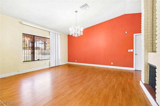 interior space featuring lofted ceiling, hardwood / wood-style floors, a notable chandelier, and a fireplace