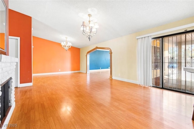 unfurnished living room with hardwood / wood-style flooring, a fireplace, a textured ceiling, and a chandelier