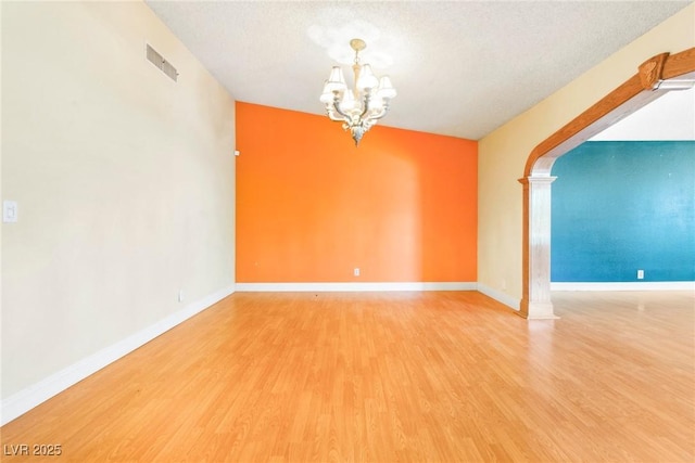 empty room with hardwood / wood-style floors, a textured ceiling, and a notable chandelier