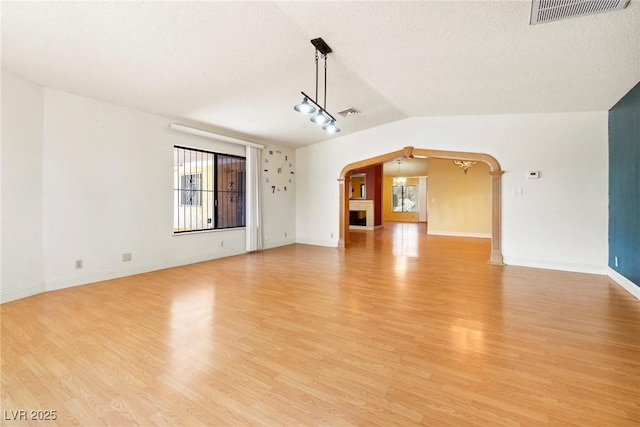 unfurnished living room featuring light hardwood / wood-style flooring, a textured ceiling, and vaulted ceiling