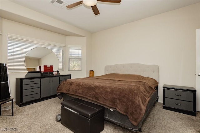 bedroom featuring a ceiling fan, visible vents, and light carpet