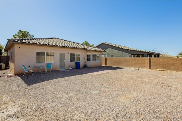 rear view of property with a tiled roof, fence, and stucco siding