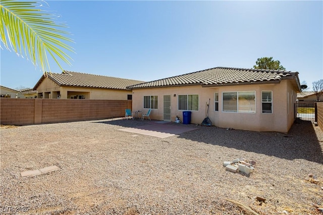 rear view of house with a patio, a tile roof, a fenced backyard, and stucco siding