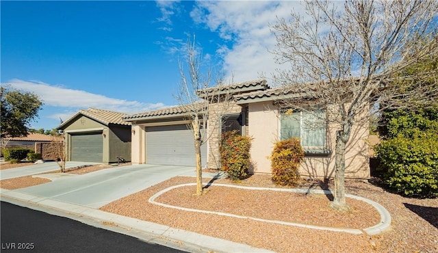 view of front facade featuring driveway, an attached garage, a tile roof, and stucco siding