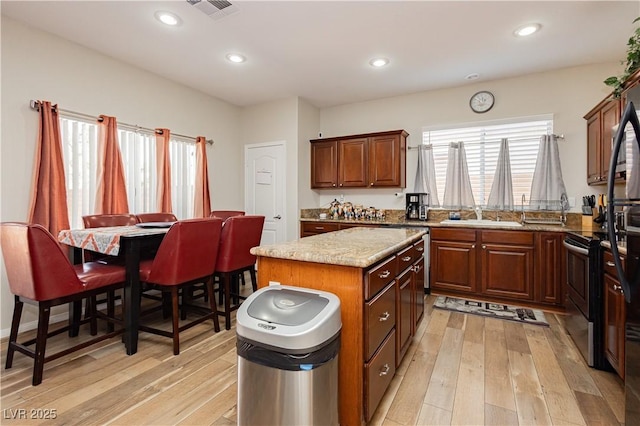 kitchen with visible vents, a kitchen island, light wood finished floors, and stainless steel electric range