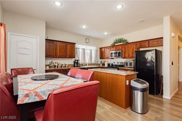 kitchen featuring recessed lighting, appliances with stainless steel finishes, light wood-type flooring, a center island, and brown cabinetry